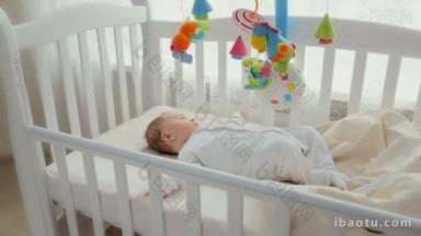 可爱的婴儿躺在摇篮与纺纱玩具旋转木马